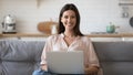 Woman sitting on couch holding computer looking at camera Royalty Free Stock Photo