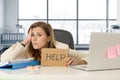 Attractive sad and desperate business woman suffering stress at office laptop computer desk holding help sign