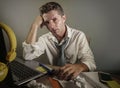 Attractive sad and desperate man in lose necktie looking messy and depressed working at laptop computer desk in business office pr Royalty Free Stock Photo