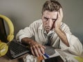 Attractive sad and desperate man in lose necktie looking messy and depressed working at laptop computer desk in business office pr Royalty Free Stock Photo