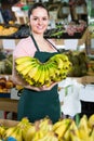 attractive salesgirl proposing fresh bananas in supermarket Royalty Free Stock Photo