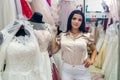 Attractive seller in bridal salon with wedding dresses