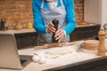 Attractive senior aged woman is cooking on kitchen. Grandmother making tasty baking. Using laptop. Close-up food concept Royalty Free Stock Photo