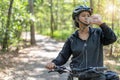 Attractive senior asian woman drinking water from bottle with bicycle Royalty Free Stock Photo