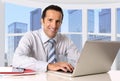 Attractive senior businessman working in business district office at computer laptop desk smiling Royalty Free Stock Photo