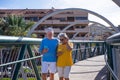 Attractive senior couple walking on a bridge in the city. Looking at their own mobile phone and smiling. Elderly modern and