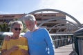 Attractive senior couple walking on a bridge in the city . Looking together at the same mobile phone. Elderly modern and