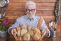 Attractive senior man with beard and white hair holds a wooden basket with fresh bread made with different flours. Rustic Royalty Free Stock Photo