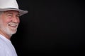 Attractive senior man with white hat and t-shirt looking at camera smiling. Portrait of elderly retired white-haired and beard. Royalty Free Stock Photo