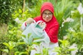 Senior muslim woman uses a watering can at garden