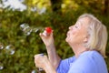 Attractive senior woman blowing soap bubbles Royalty Free Stock Photo