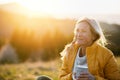 Attractive senior woman sitting outdoors in nature at sunset, relaxing with coffee. Royalty Free Stock Photo