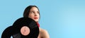 Attractive sensual young woman with red color lips looking up holding two music records retro in her hands over turquose