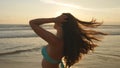 Attractive girl with long hair posing on the ocean shore at sunrise. Beautiful young woman in bikini standing near Royalty Free Stock Photo