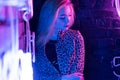 Sexy girl wear stylish leopard jacket standing near wall with purple neon light