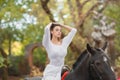 Horseback riding. Beautiful young woman in a white dress riding on a brown horse outdoors. Royalty Free Stock Photo