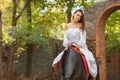 Horseback riding. Beautiful young woman in a white dress riding on a brown horse outdoors. Royalty Free Stock Photo