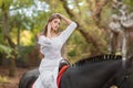 Horseback riding. Beautiful young woman in a white dress riding on a brown horse outdoors. Royalty Free Stock Photo