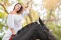 Horseback riding. Beautiful young woman in a white dress riding on a brown horse outdoors. Royalty Free Stock Photo