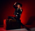 Attractive sexy young blonde woman model in black leather leggins, boots, jacket, hat and accessories sitting on retro Royalty Free Stock Photo