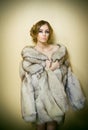 Attractive young woman wearing a fur coat posing provocatively indoor. Portrait of sensual female with creative haircut Royalty Free Stock Photo