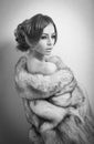 Attractive young woman wearing a fur coat posing provocatively indoor. Portrait of sensual female with creative haircut