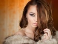 Attractive young woman wearing a fur coat posing provocatively indoor. Portrait of sensual female with creative makeup