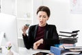 Attractive shocked businesswoman holding hourglass and checking time with wristwatch Royalty Free Stock Photo