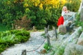 Attractive shoeless happy young blonde woman in stylish red white dress posing on path at hill. standing on road village and