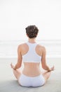 Attractive slim brown haired model in white sportswear meditating in lotus position