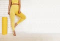 Cropped shot of fit female legs in yellow sports leggings and yoga pants standing near wall.. Royalty Free Stock Photo