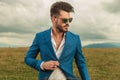 Attractive smart casual man with sunglasses buttoning blue suit