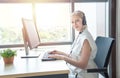 Attractive and smile young caucasian customer servicer woman wearing headset in modern creative meeting working office sit at Royalty Free Stock Photo