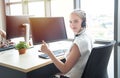 Attractive and smile young caucasian customer servicer woman wearing headset in modern creative meeting working office sit at Royalty Free Stock Photo