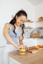 Attractive smiling Asian woman makes fresh tasty healthy orange juice in the kitchen. A beautiful young Korean girl squeezes an Royalty Free Stock Photo