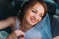 Attractive smiling bride in white veil sitting in car looking towards Royalty Free Stock Photo