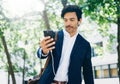 Attractive smiling businessman using smartphone for listining music while walking in city park.Horizontal,blurred Royalty Free Stock Photo