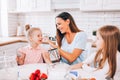 An attractive smiling family of mother and two daughters baking in a light kitchen at home. Sibling rivalry Royalty Free Stock Photo