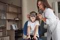 Attractive smiling female doctor loving her job. Little girl in glasses sitting in clinic and having her eyes tested Royalty Free Stock Photo