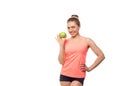 Attractive smiling fit caucasian woman in pink sports top holds a green apple in hand, isolated on white. Girl promotes Royalty Free Stock Photo