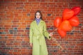 Attractive smiling lady in coat with red air balloons