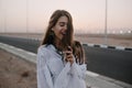 Attractive smiling long-haired girl posing with eyes closed while walking down the road in summer evening. Portrait of Royalty Free Stock Photo