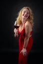 Attractive smiling mature woman in red evening dress with glass of red wine Royalty Free Stock Photo