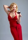 Attractive smiling mature woman in red evening dress with glass of red wine Royalty Free Stock Photo