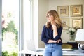 Attractive smiling mature woman standing at desk and thinking Royalty Free Stock Photo