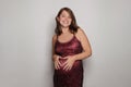 Attractive smiling pregnant woman making heart from hand on her belly while standing against grey studio wall banner background Royalty Free Stock Photo