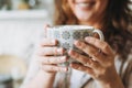 Attractive smiling woman with curly hair in plaid shirt with cup of cacao with marshmallow, cozy winter christmas mood