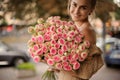 attractive smiling woman with great bouquet of roses in her hands looks at the camera Royalty Free Stock Photo