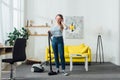 Smiling woman in headphones cleaning carpet