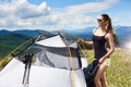 Woman tourist hiking in mountain trail, enjoying summer sunny morning in mountains near tent Royalty Free Stock Photo